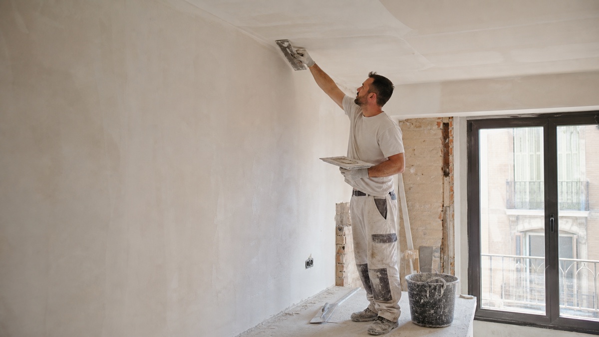 Yesero aplicando enlucido en el techo de una habitación en reforma